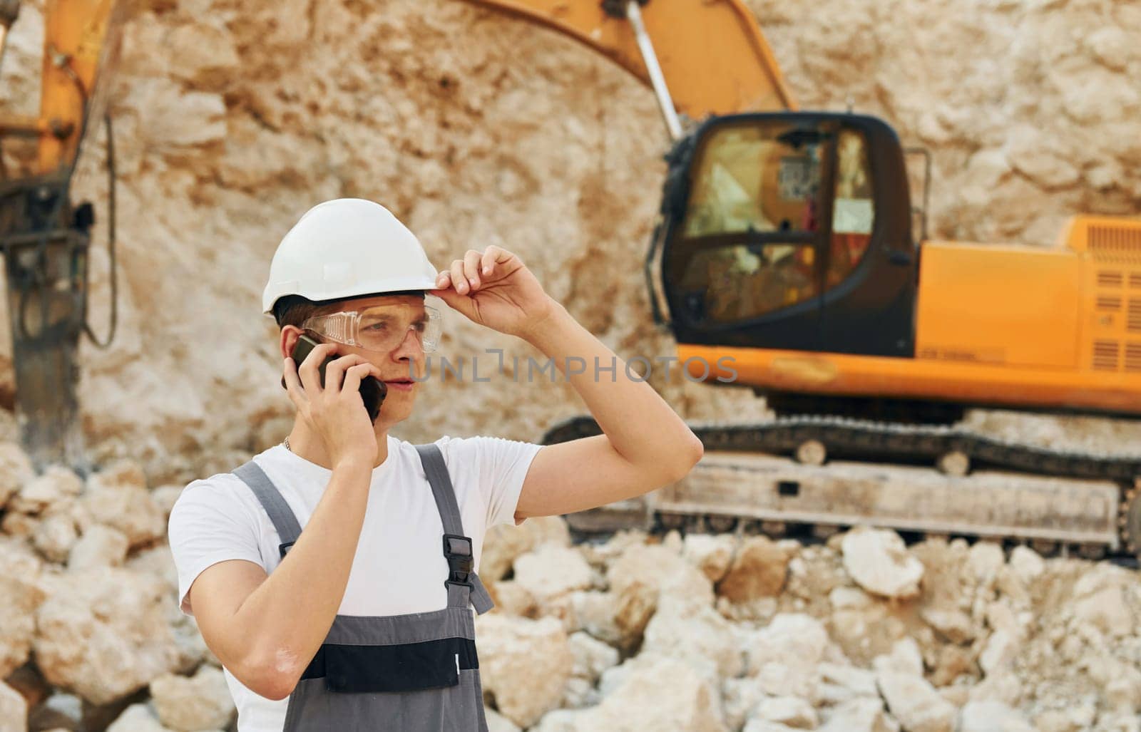 Big career. Worker in professional uniform is on the borrow pit at daytime.