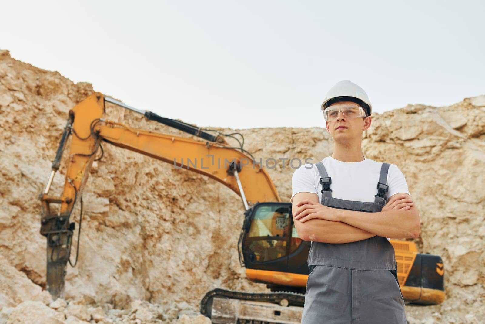 Big career. Worker in professional uniform is on the borrow pit at daytime.