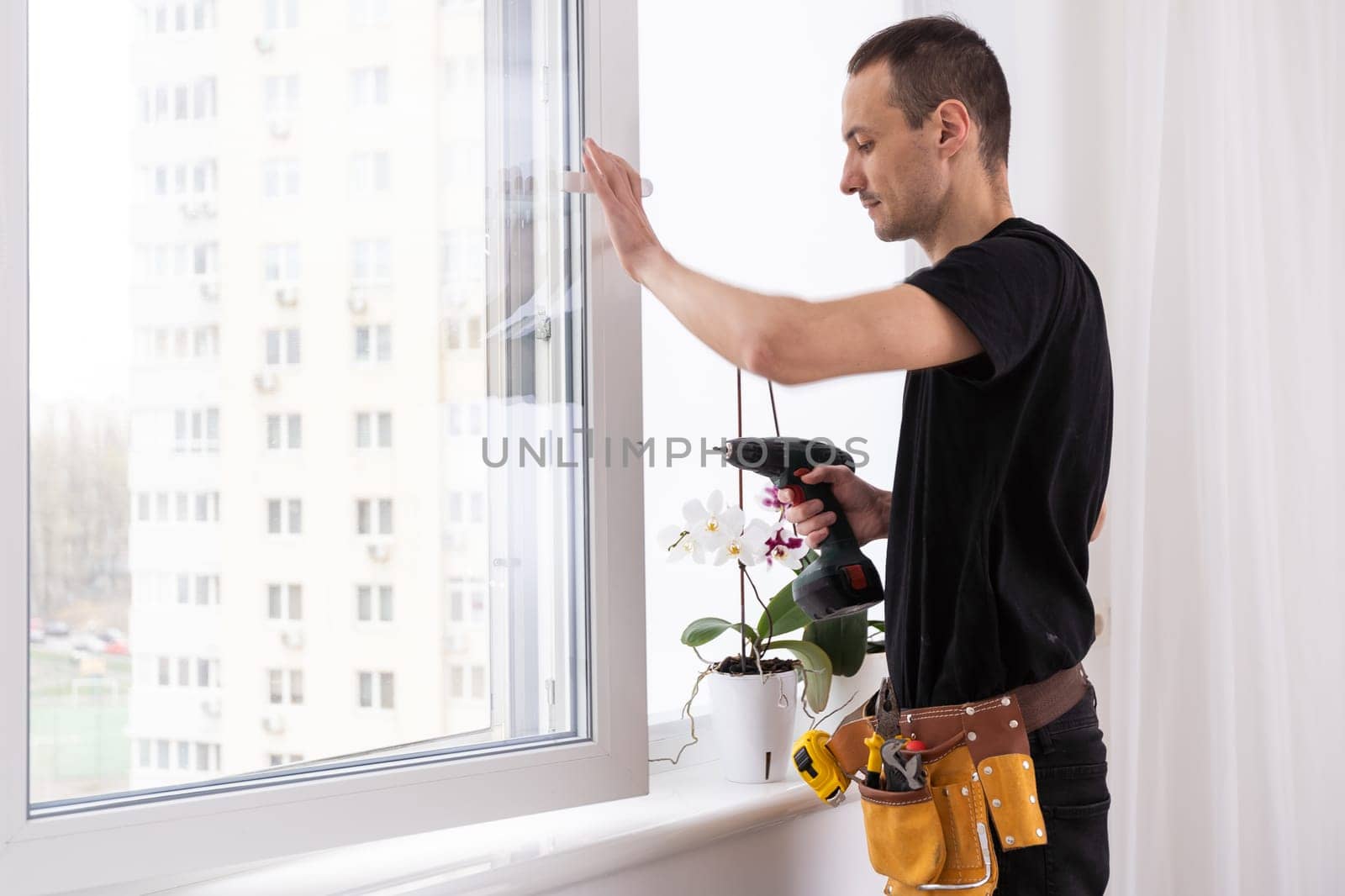 service man installing window with screwdriver by Andelov13