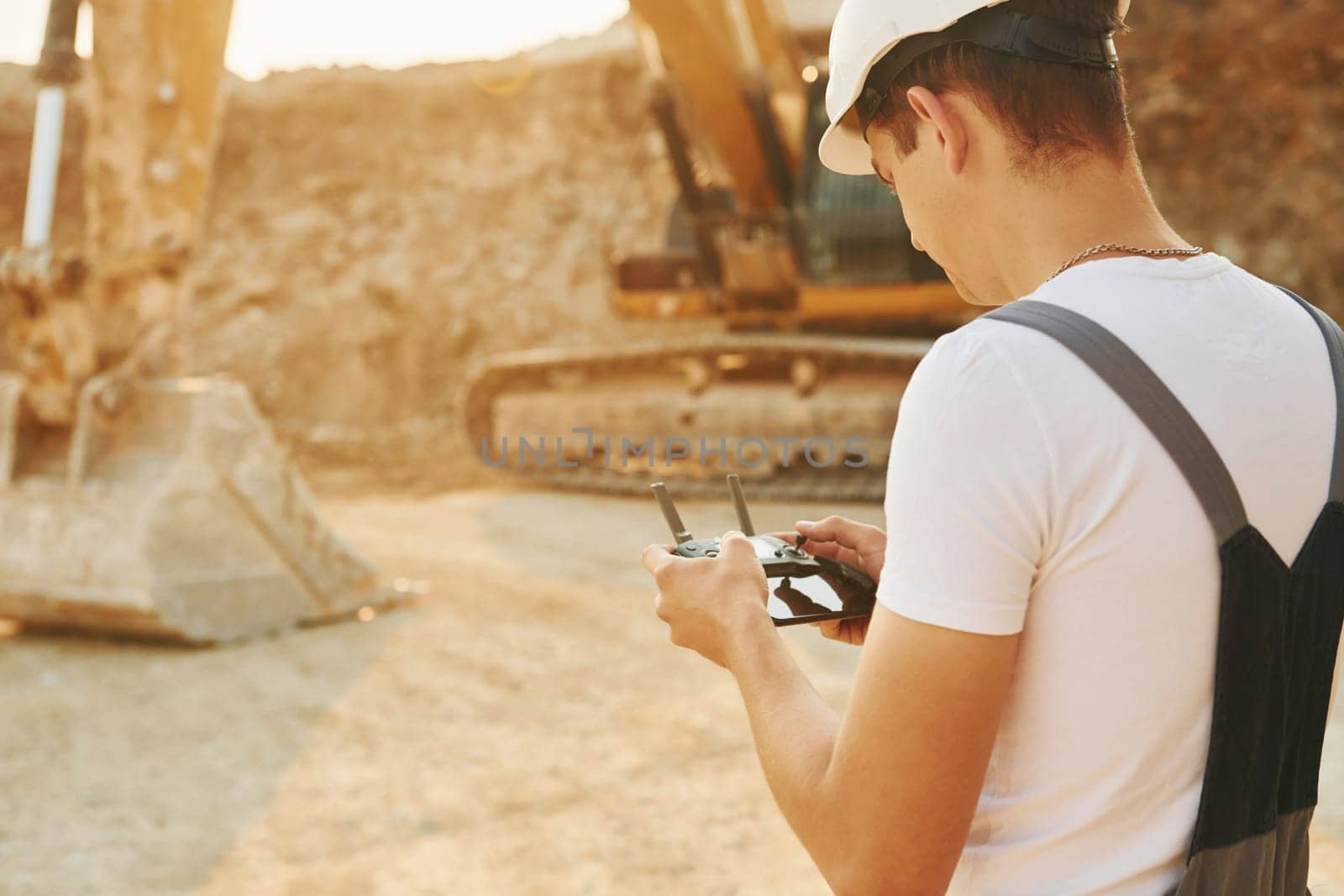 Control of the project. Worker in professional uniform is on the borrow pit at daytime.