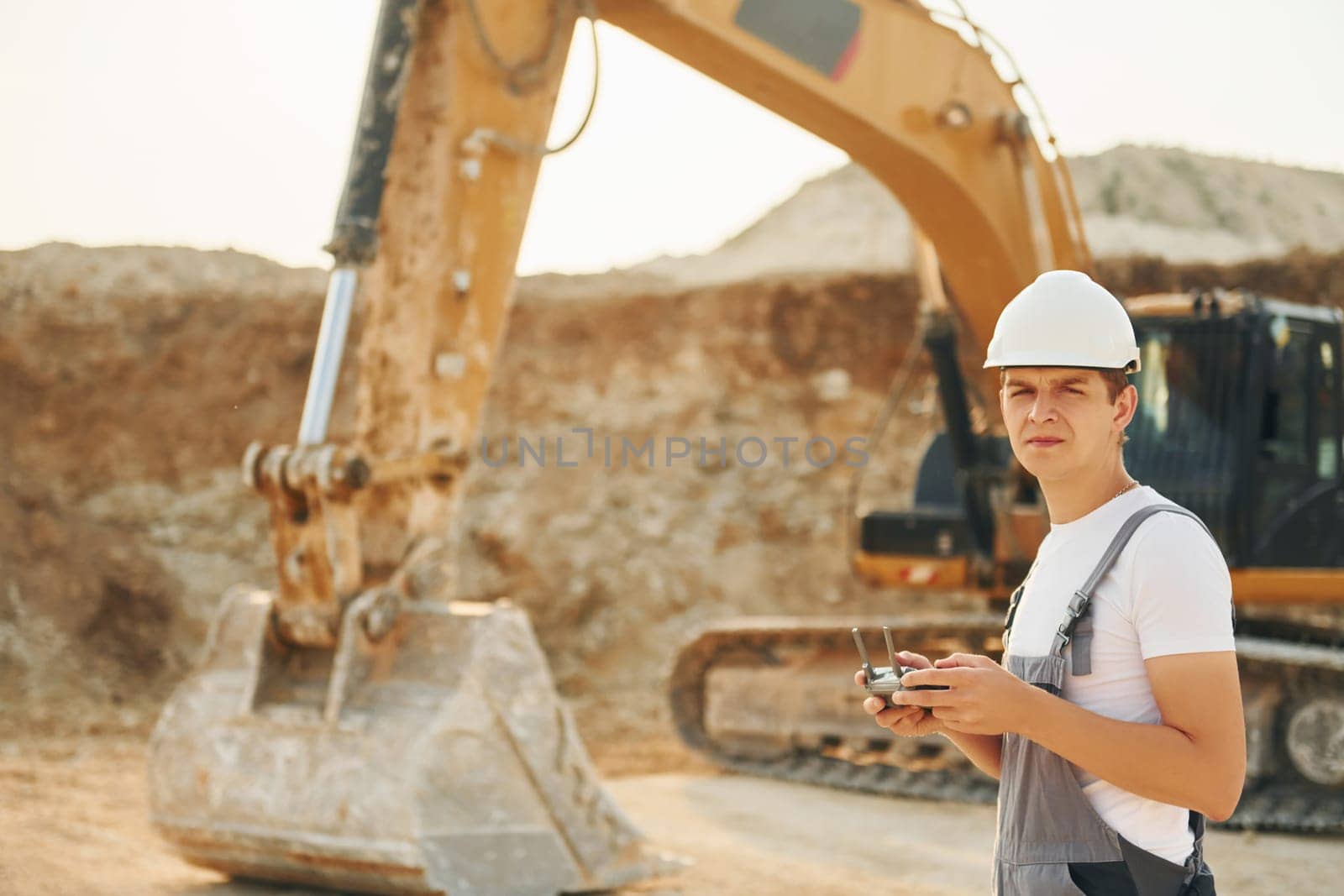 Illuminated by sunlight. Worker in professional uniform is on the borrow pit at daytime.