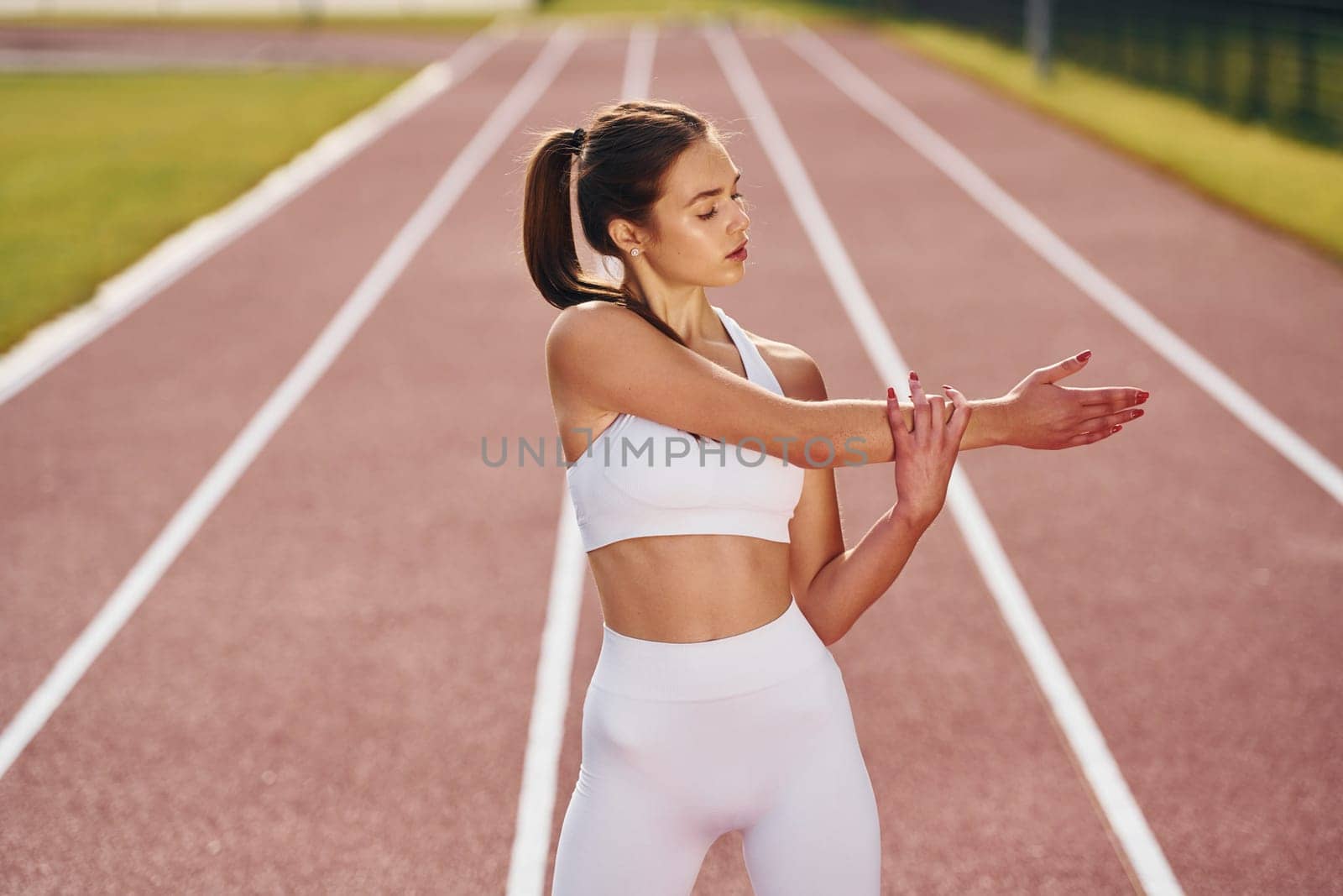Standing and practicing. Young woman in sportive clothes is exercising outdoors.