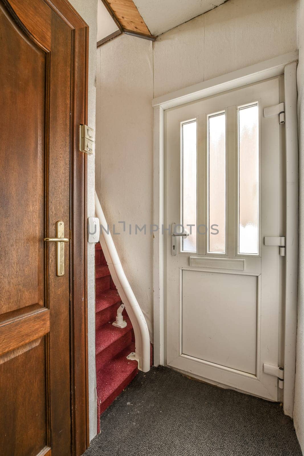 a room with a red carpet and a white door that is open to reveal the stairs in front of it