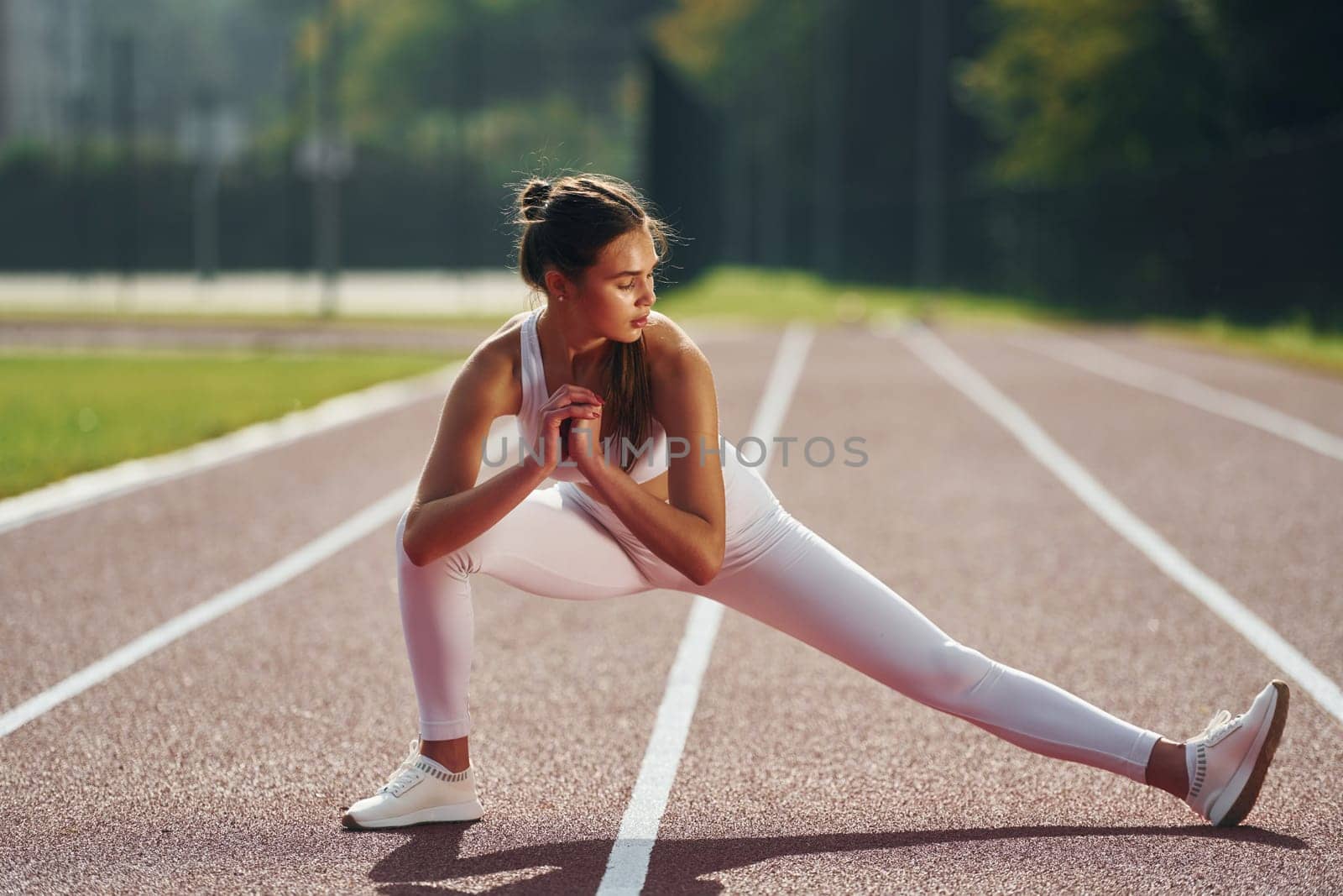 Front view. Young woman in sportive clothes is exercising outdoors.