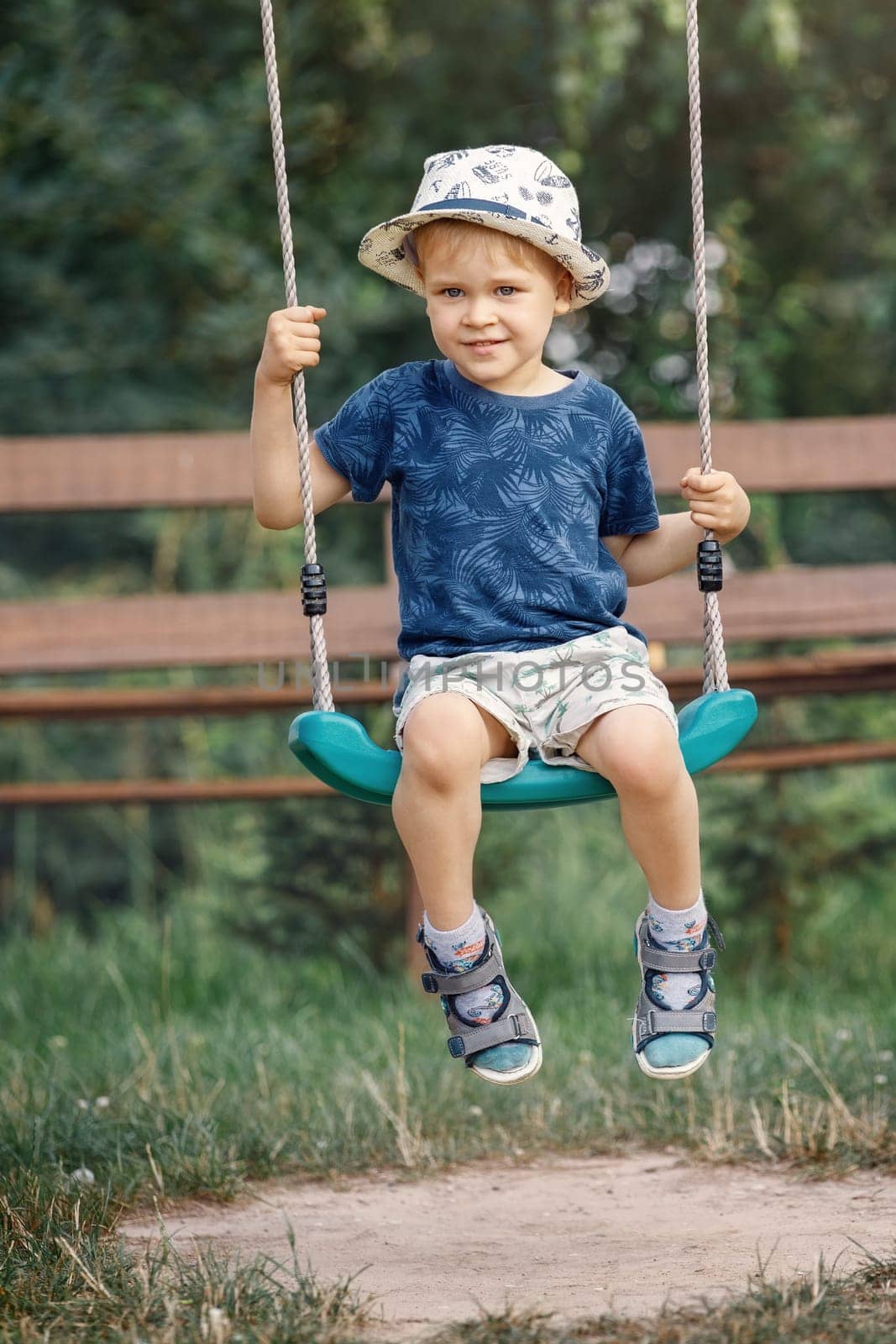 Little boy playing on swing in backyard at countryside.