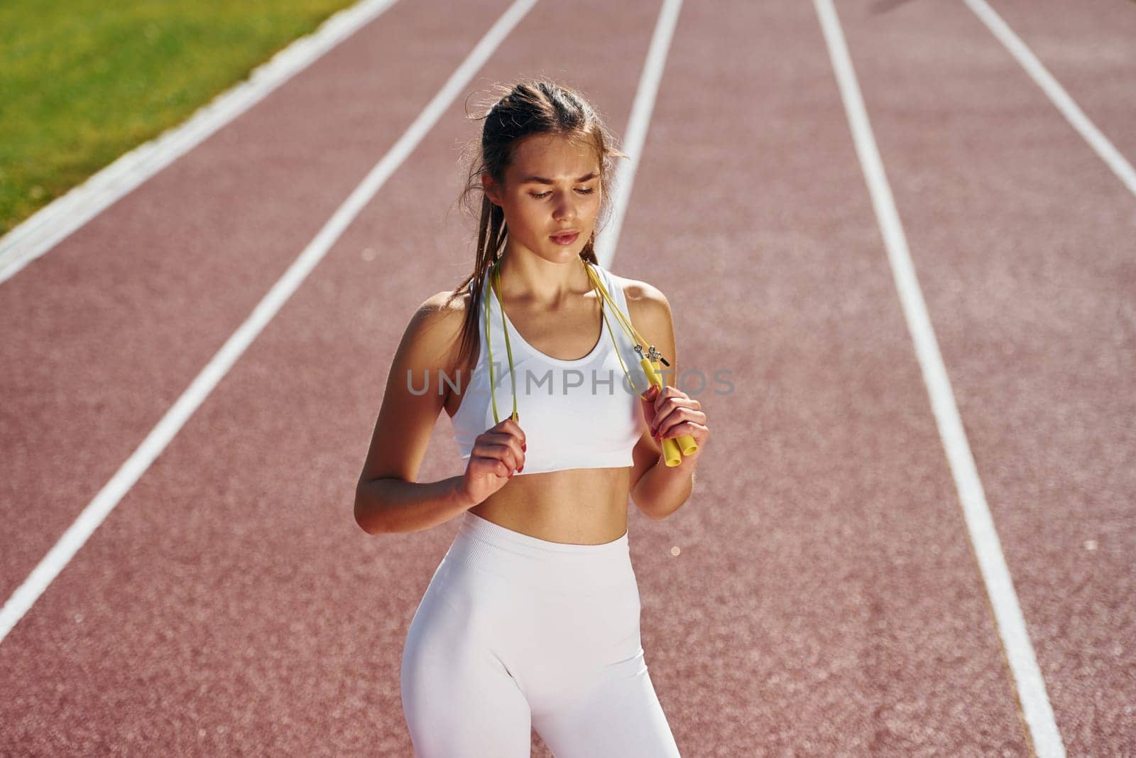 Standing and looking at the camera. Young woman in sportive clothes is exercising outdoors.