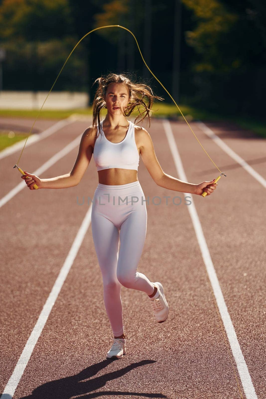 Practicing with jumping rope. Young woman in sportive clothes is exercising outdoors.