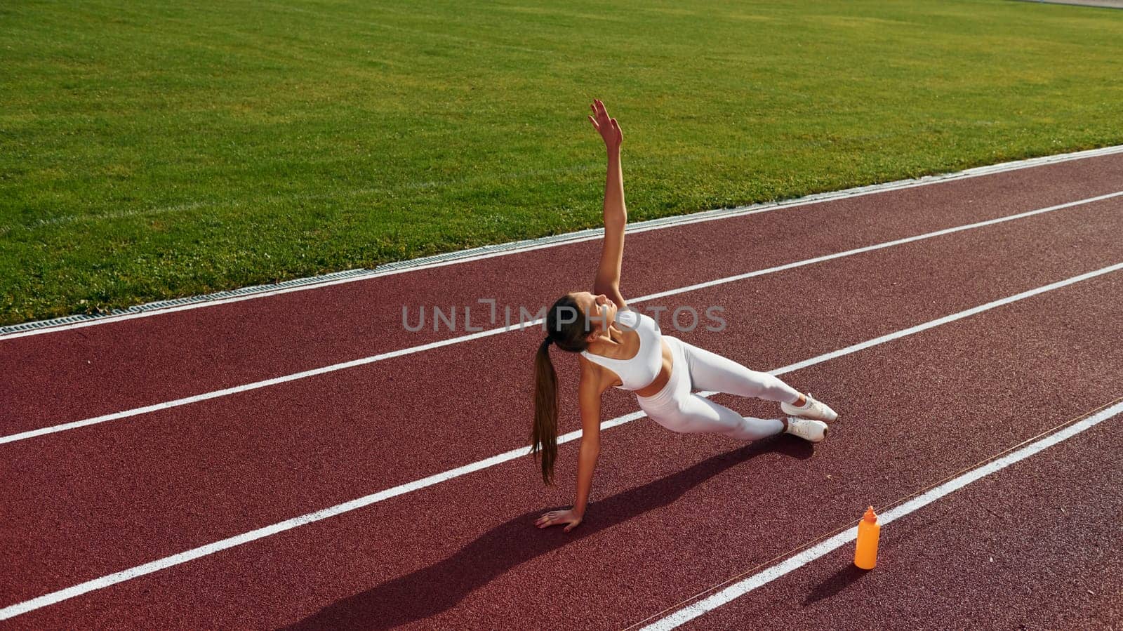 Woman is on the running track exercising outdoors.