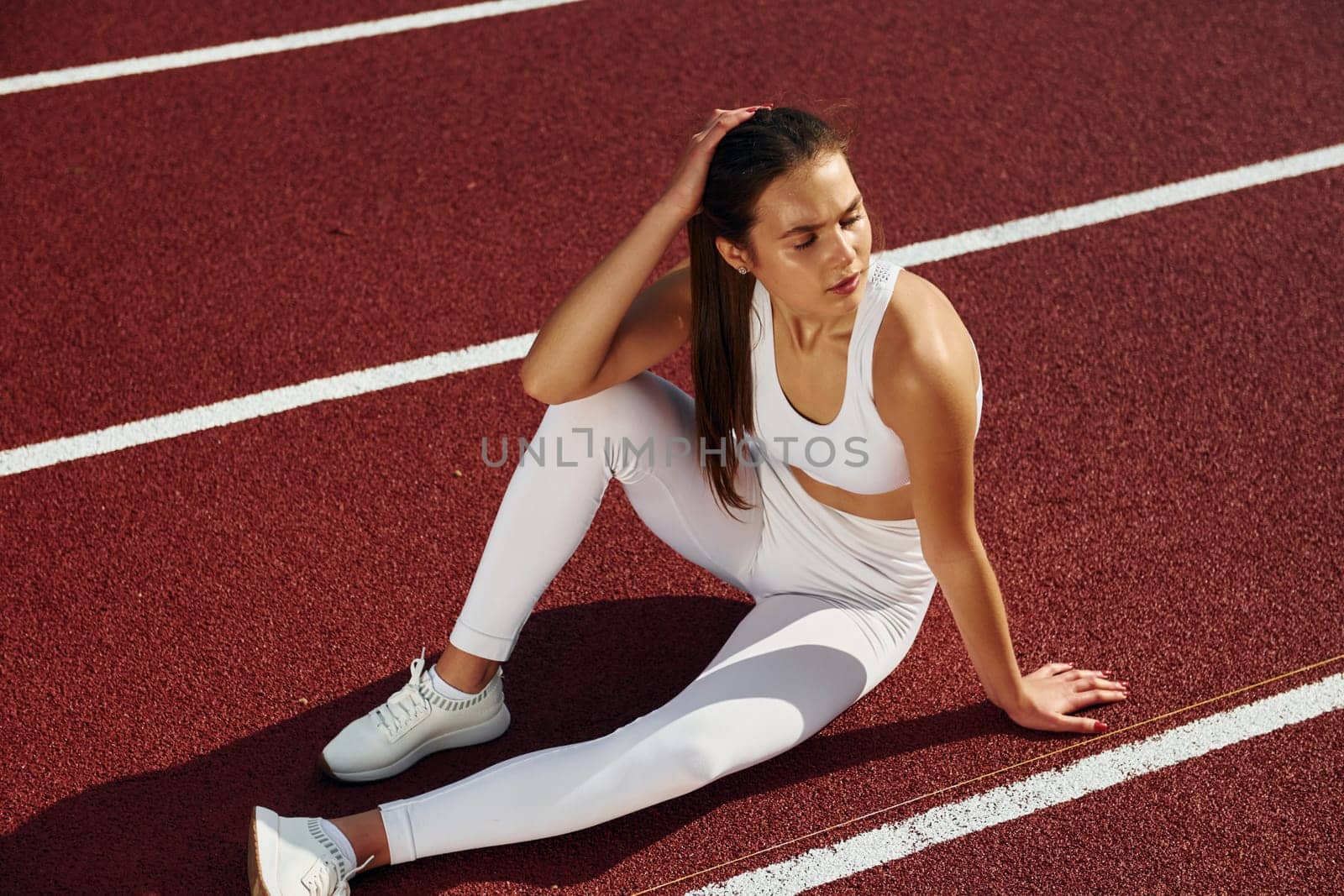 Sitting and taking a break. Young woman in sportive clothes is exercising outdoors.