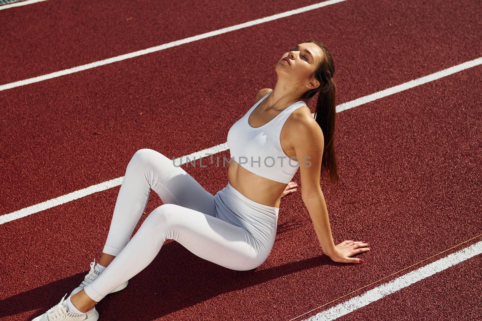 Tired, taking break. Young woman in sportive clothes is exercising outdoors.