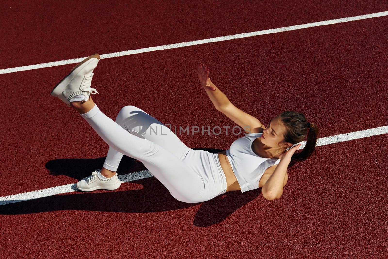Doing abs. Young woman in sportive clothes is exercising outdoors.
