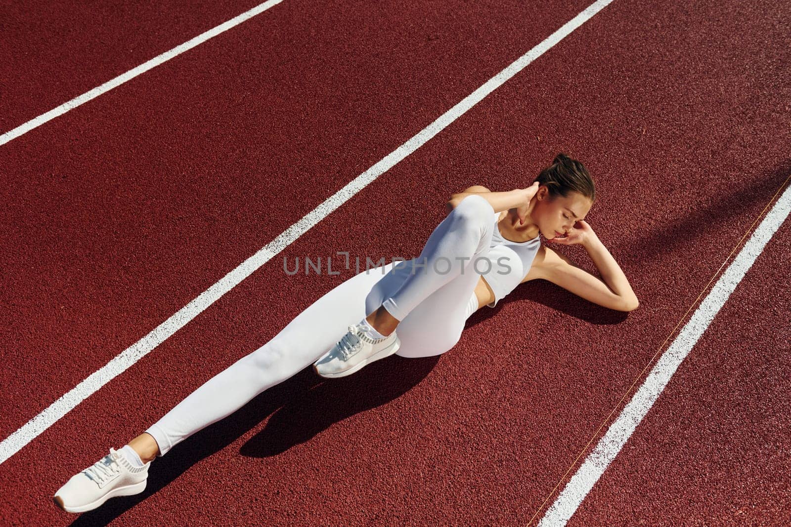 Doing abs. Young woman in sportive clothes is exercising outdoors.