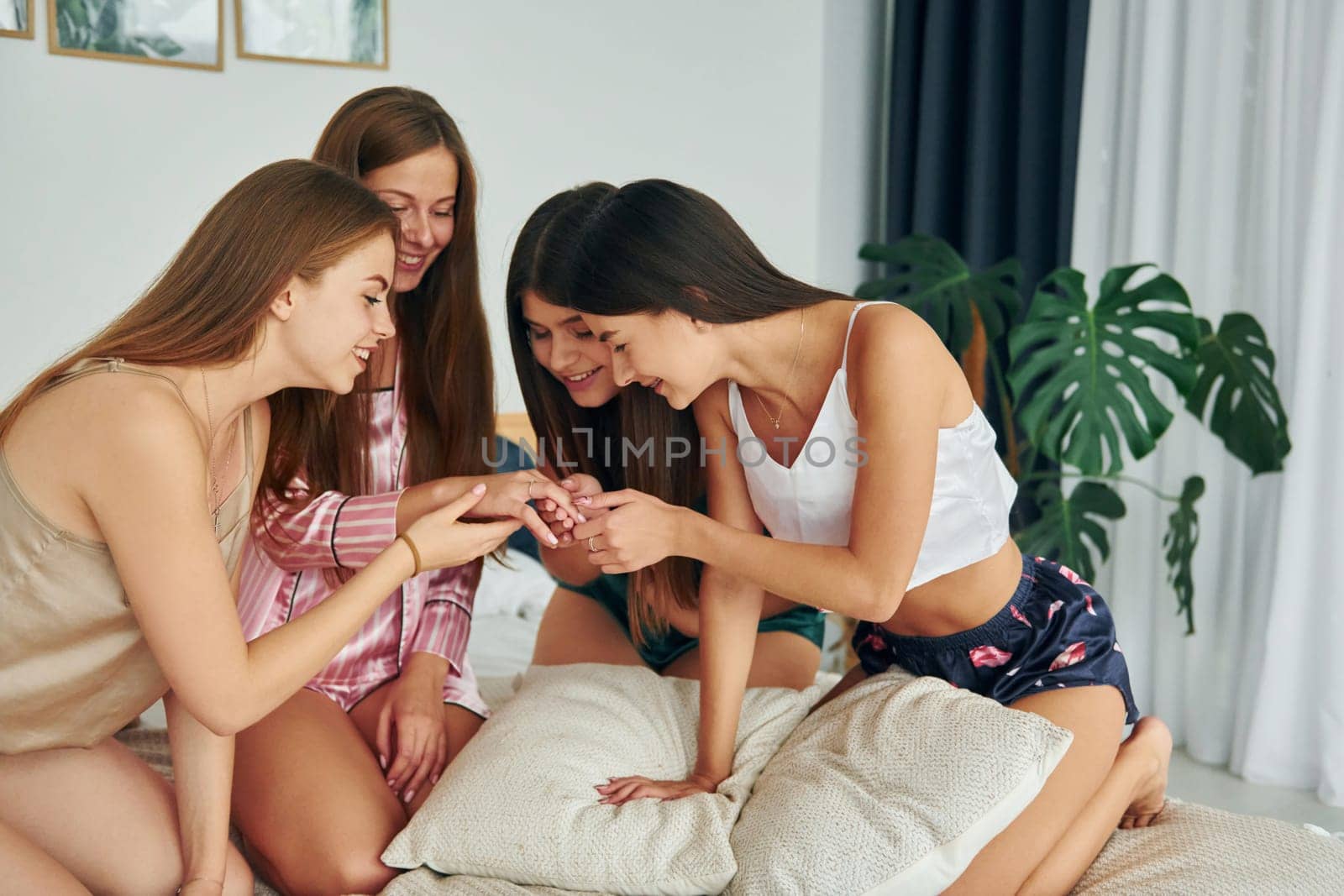 Sitting on the bed. Group of happy women that is at a bachelorette party.