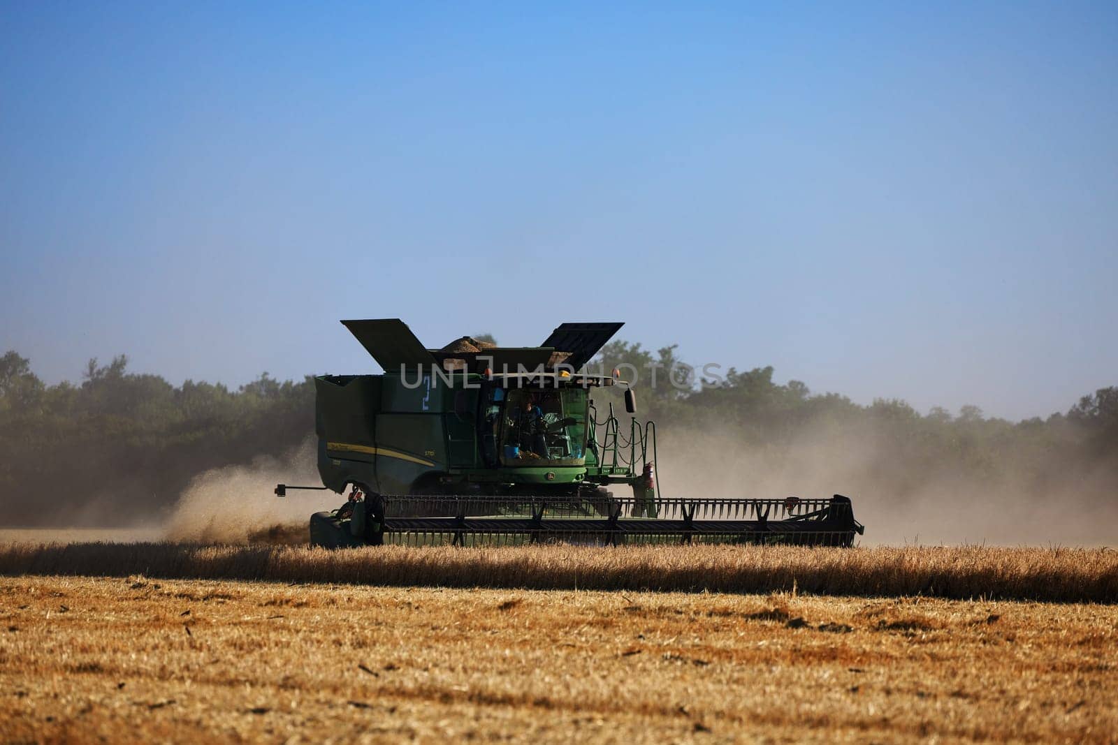 John Deere harvester works in the field. Combine Harvesting Wheat. Field field of cereals during harvesting. Modern equipment works. 07.07.22, Rostov region, Russia.