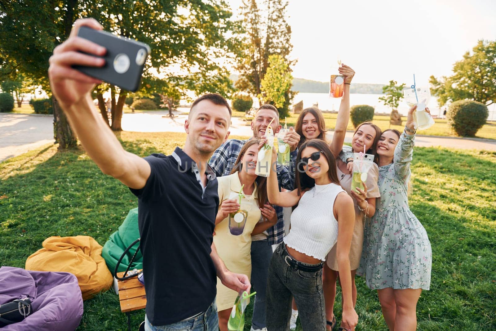 Man taking a selfie. Group of young people have a party in the park at summer daytime.