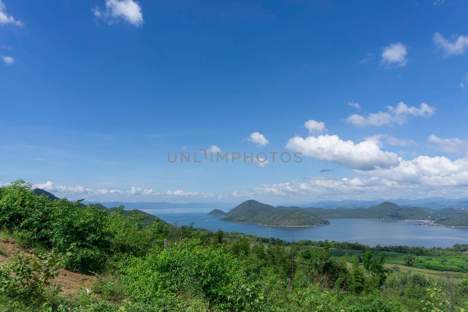 Clear blue sky white clouds, trees, natural grass trees around the Srinakarin Reservoir, Kanchanaburi, Thailand