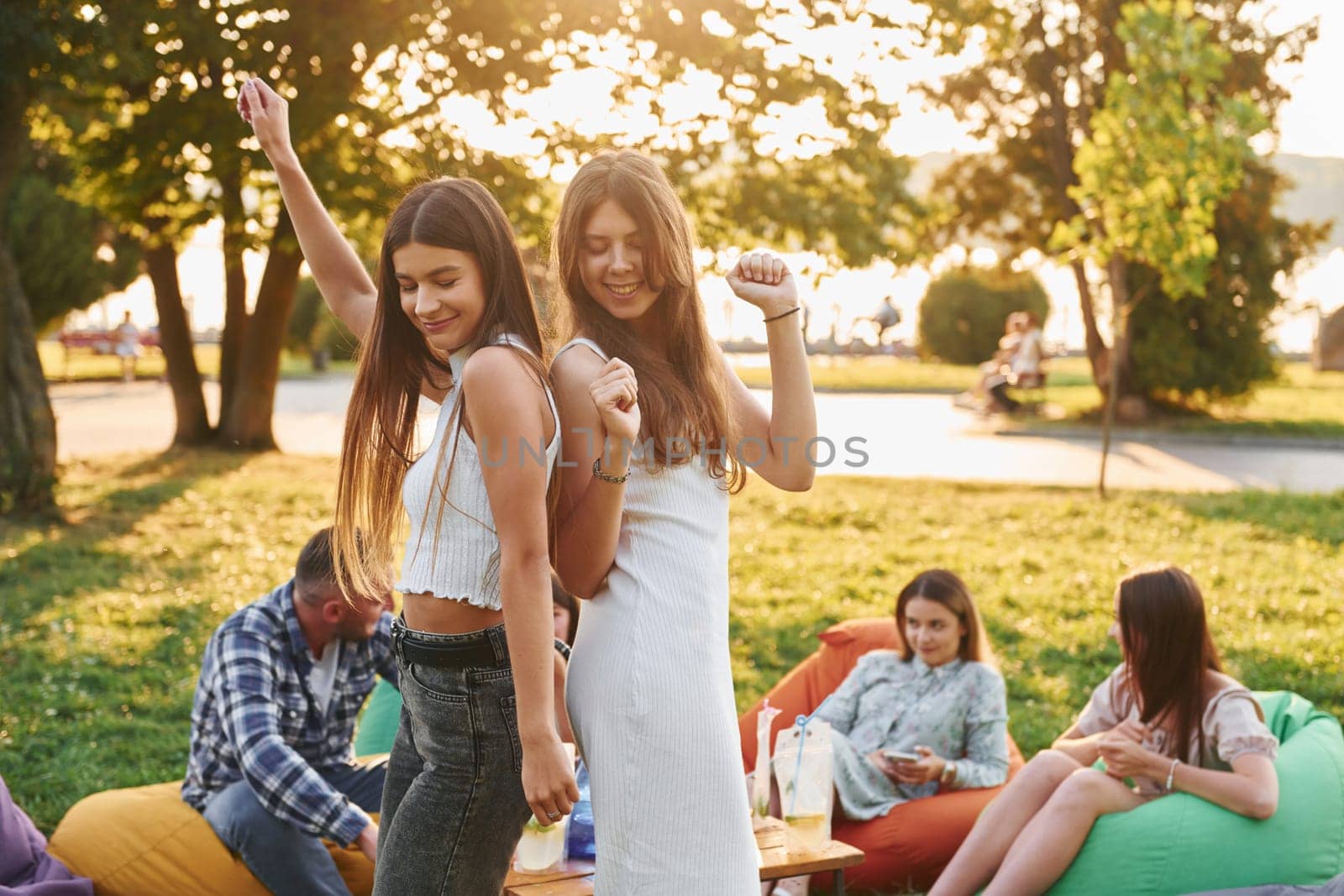 Standing and having fun. Group of young people have a party in the park at summer daytime.