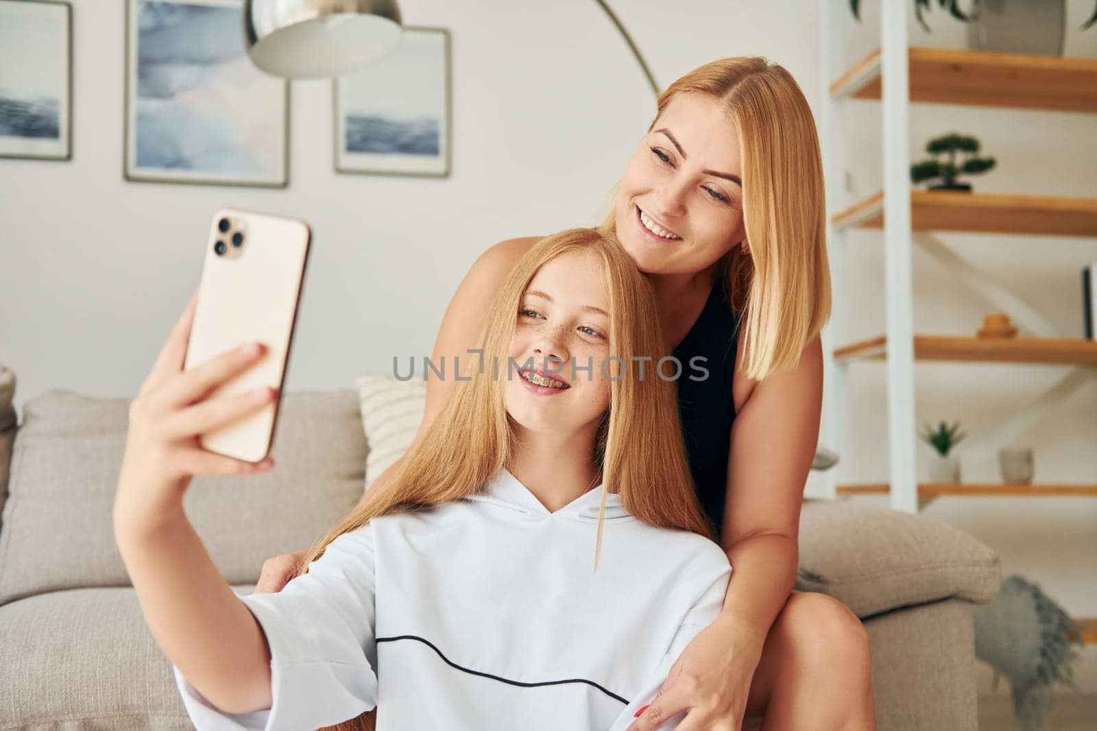 Making selfie. Female teenager with her mother is at home at daytime.