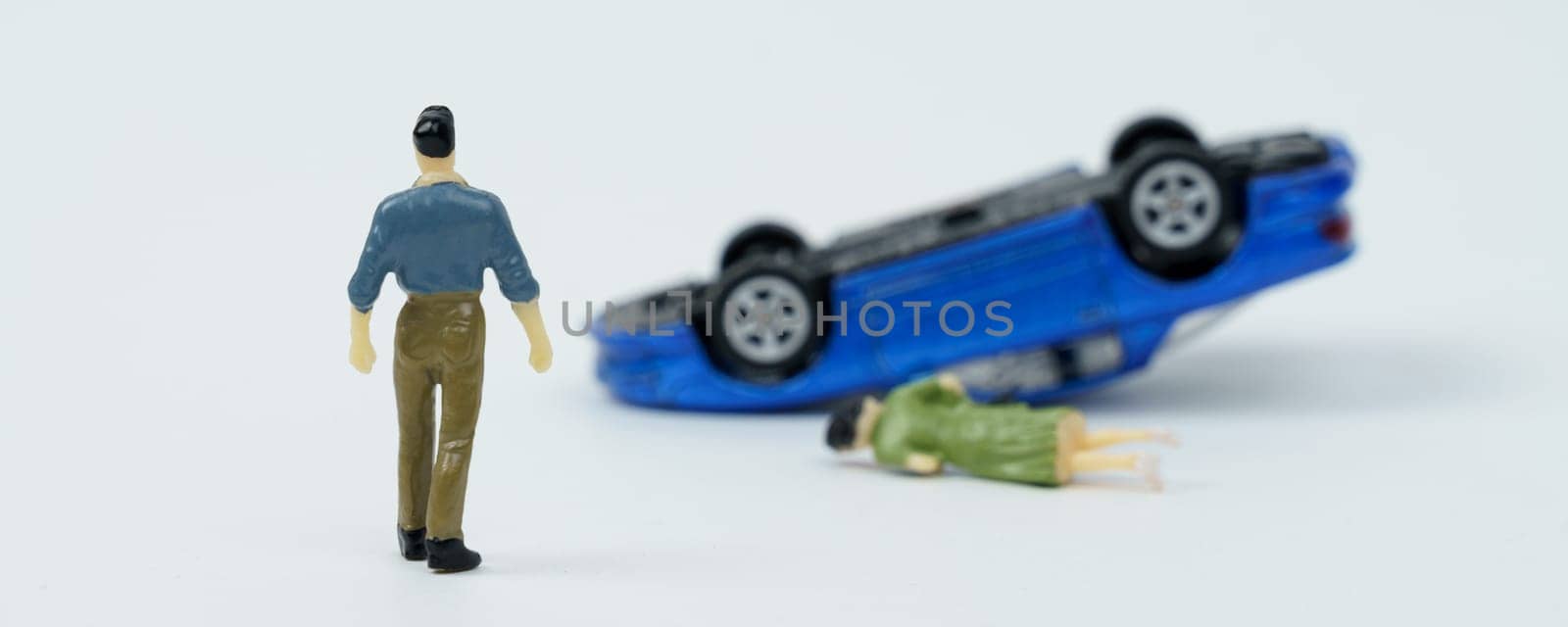 On a white background, a man who is walking towards a car overturned as a result of an accident and a woman lying down.