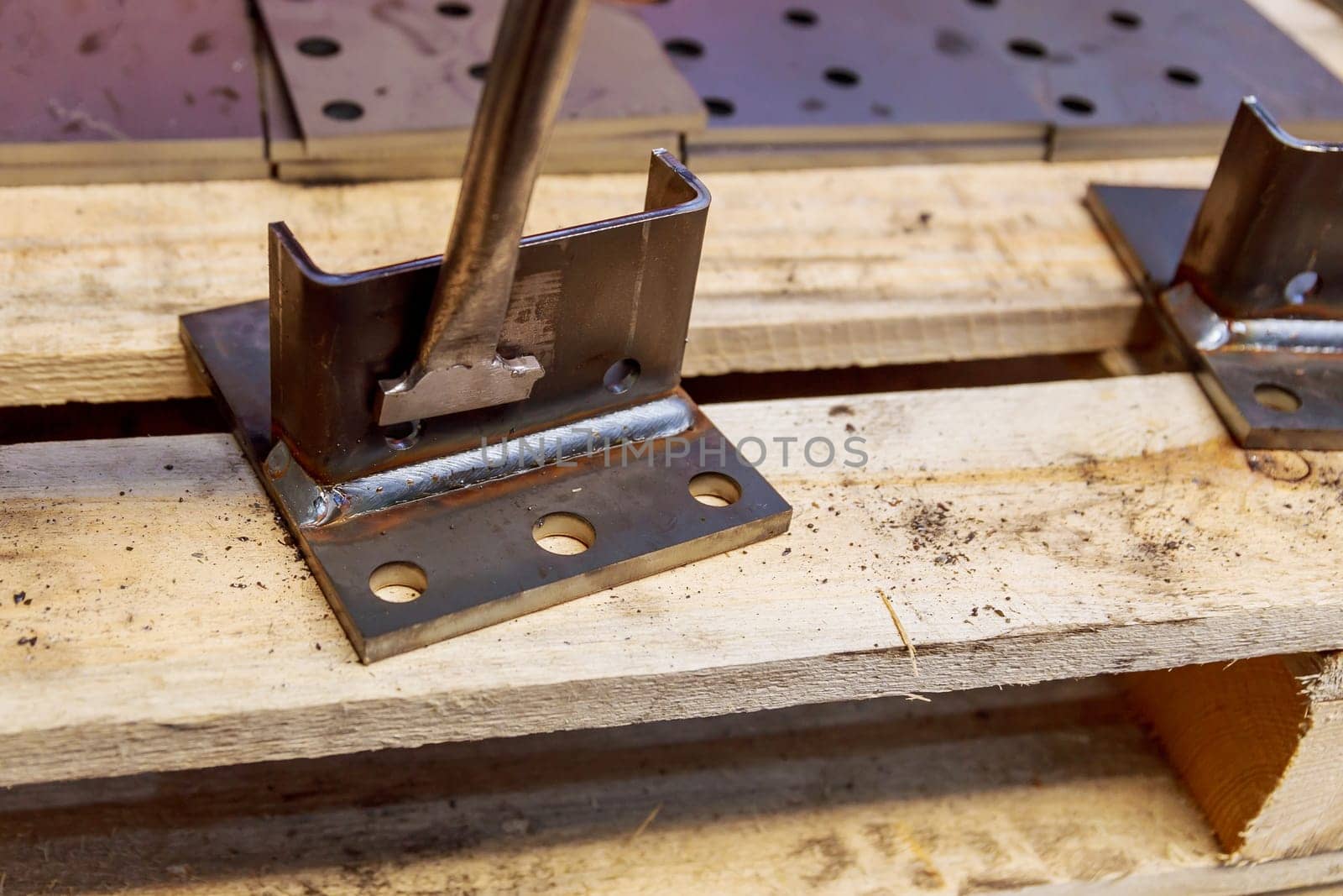 The worker cleans the welding seam with the help of a special home-made tool from balls formed during welding.