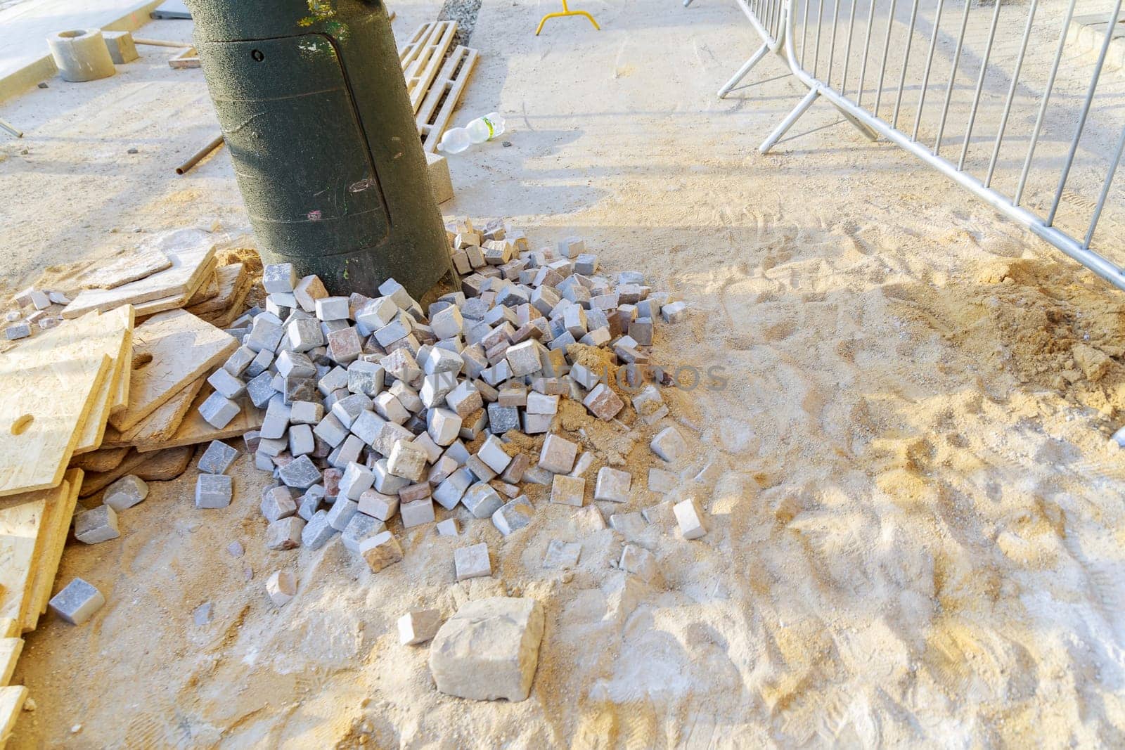 Road works to restore the pavement. Paving stones are poured on sand at the place of repair of the pavement. Arrangement of a pedestrian zone in the city. Building material.