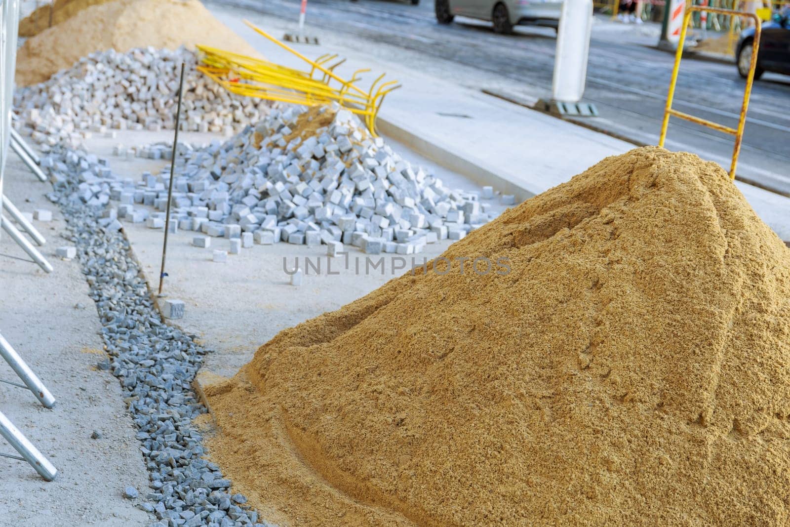 A pile of sand lying on a new pavement for paving and jointing. reconstruction of the pedestrian zone. Laying paving stones of white and gray color, small size in the city.