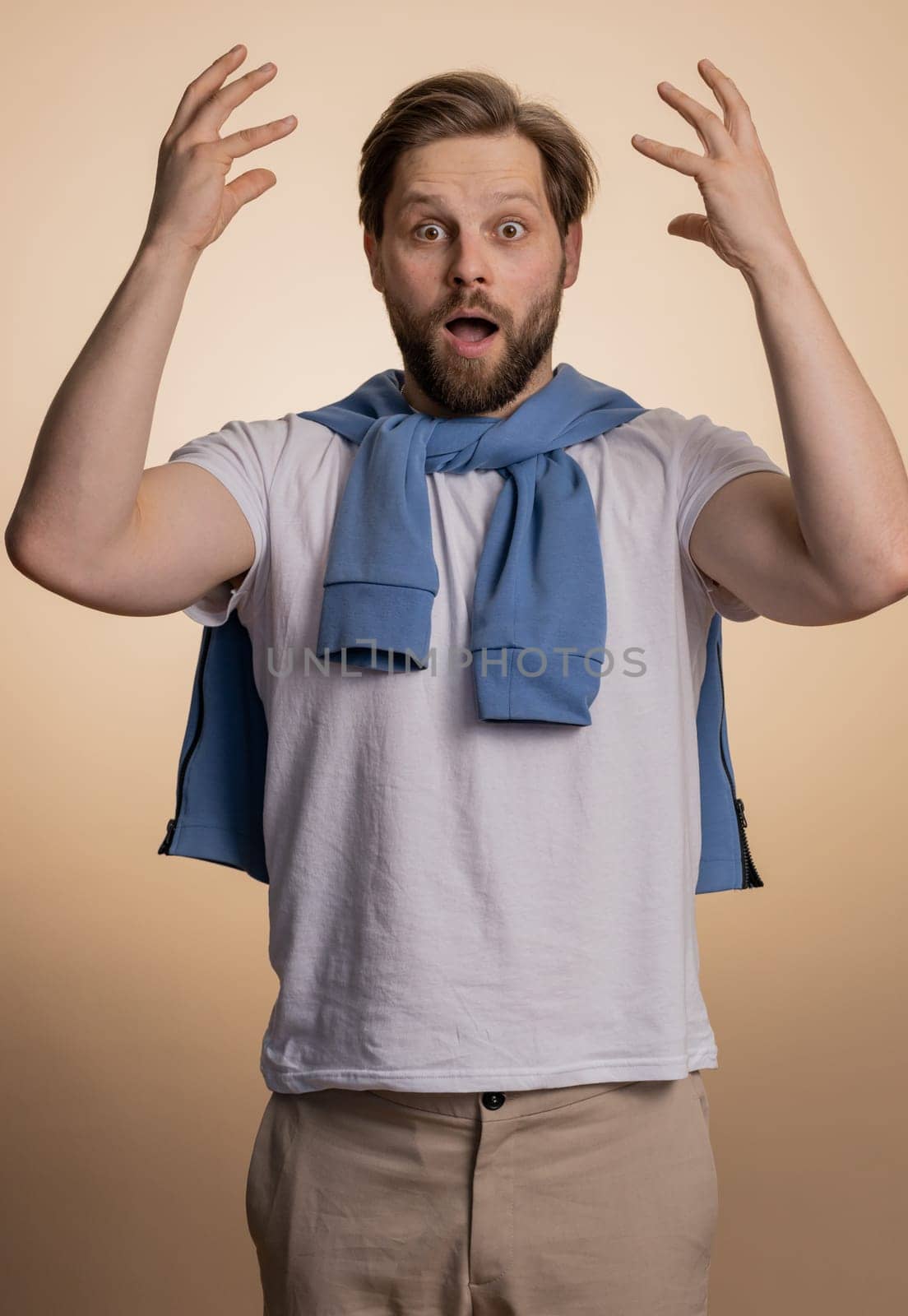 Excited amazed caucasian man touching head and showing explosion, looking worried and shocked, celebrating success idea. Looking surprised of win wow guy isolated alone on beige studio background