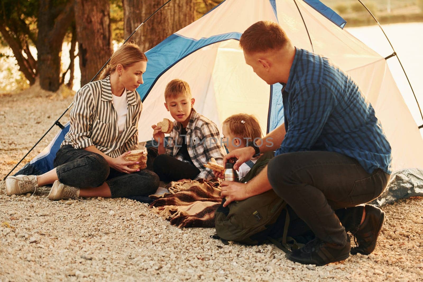 Sitting on the ground. Family of mother, father and kids is on the camping.