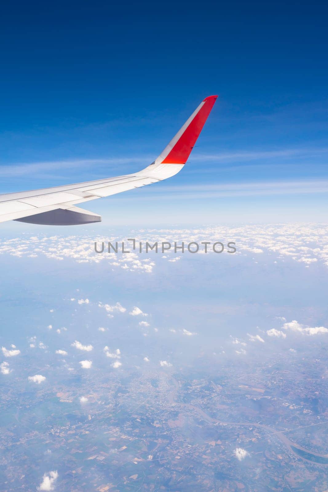 Aerial, earth, land, cloud with airplane wing from airplane window.