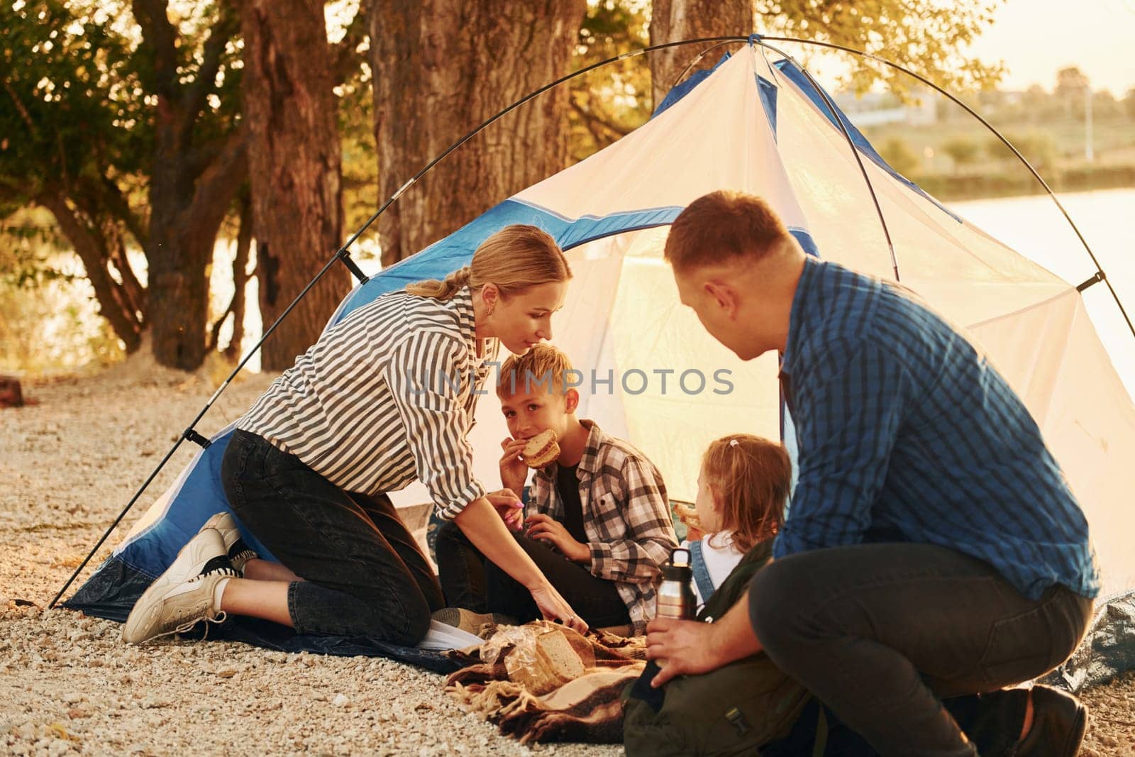 Sitting on the ground. Family of mother, father and kids is on the camping.