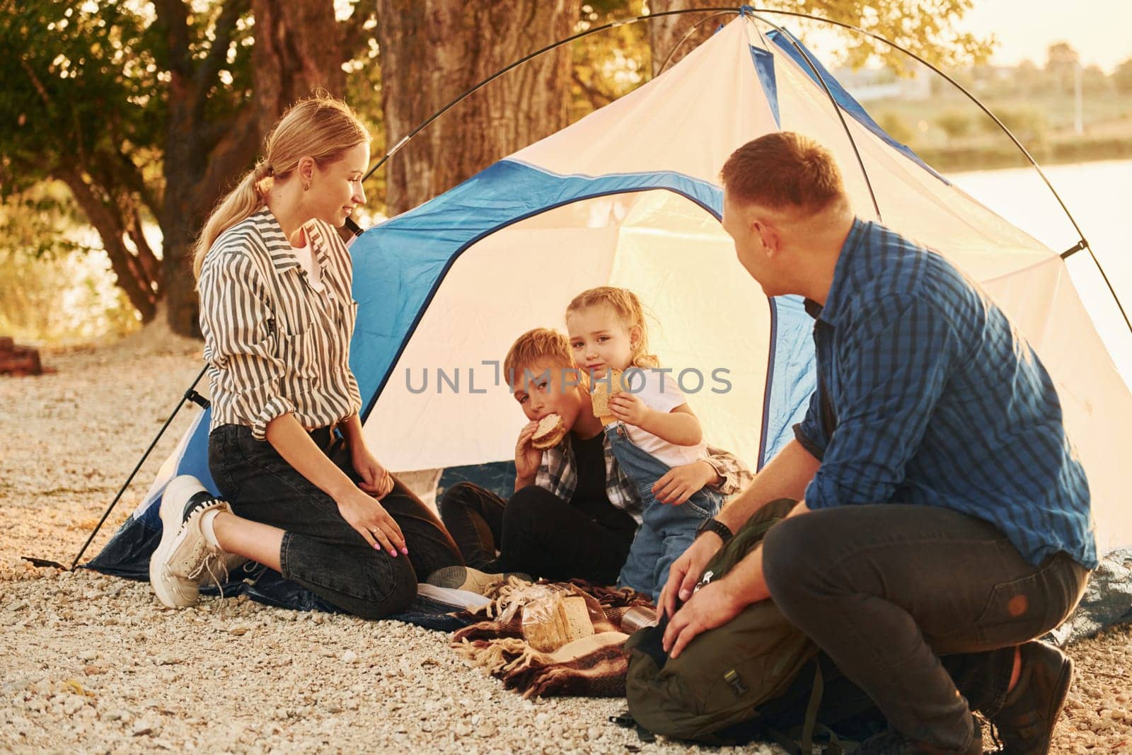 Sitting on the ground. Family of mother, father and kids is on the camping.