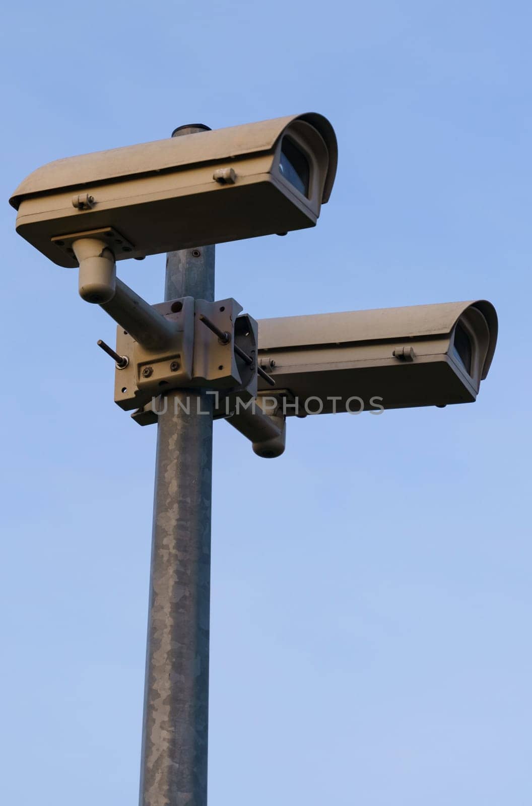 Surveillance cameras mounted on a pole against the blue sky. Video surveillance systems. Vertical frame.