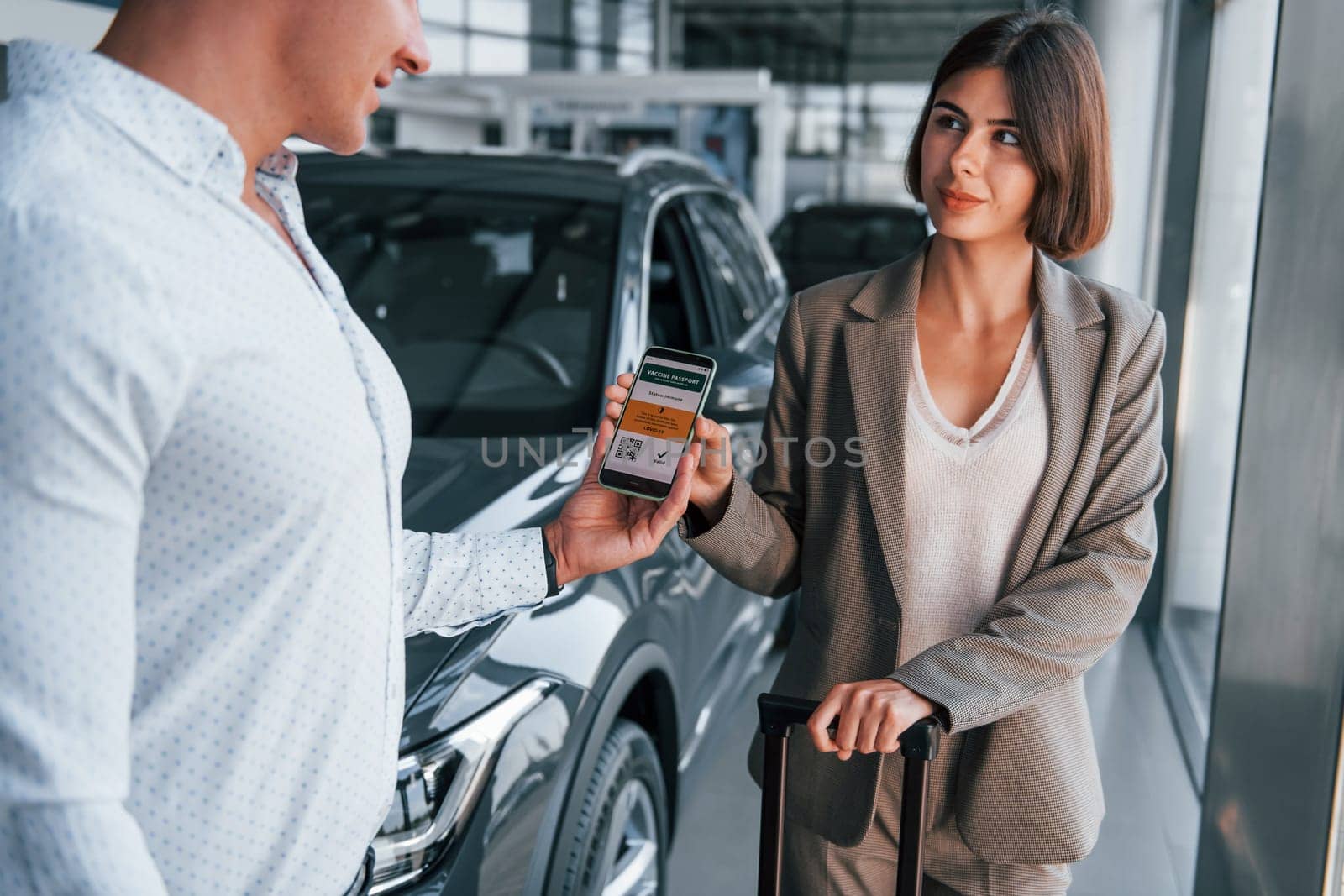 Woman showing her vaccine passport by using smartphone to the man.