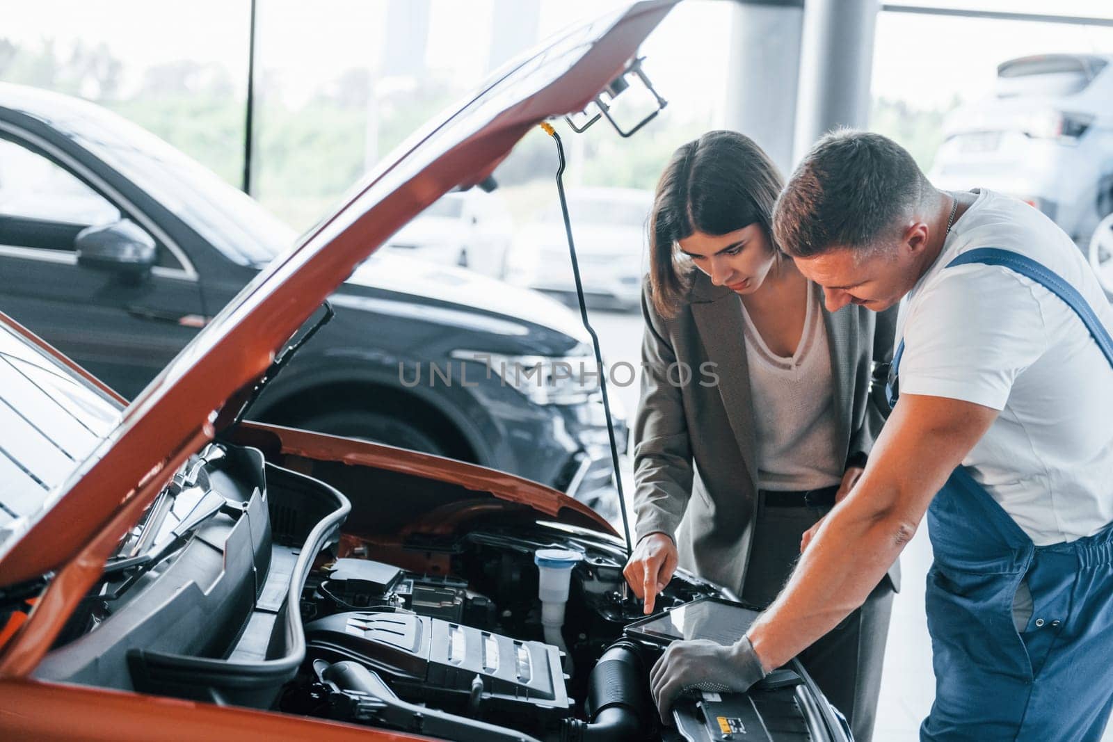 Showing results of work. Man repairing woman's automobile indoors. Professional service.