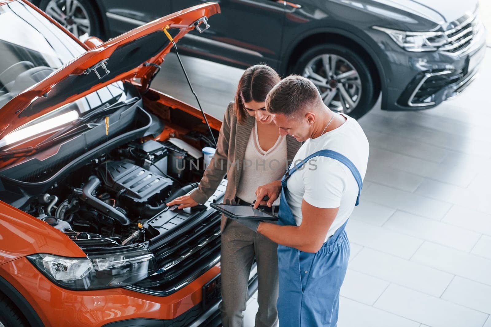 Showing results of work. Man repairing woman's automobile indoors. Professional service.