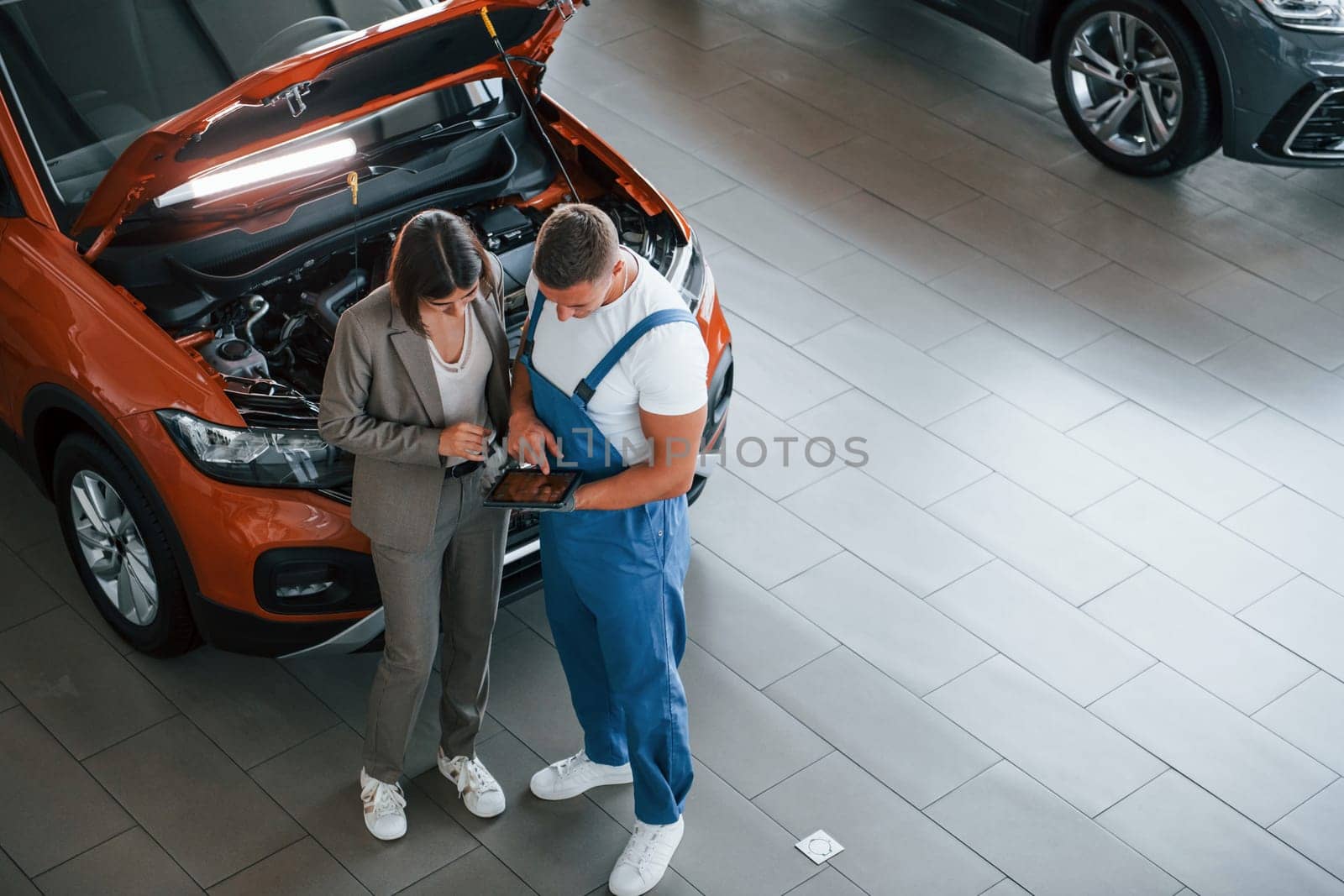 Showing results of work. Man repairing woman's automobile indoors. Professional service.
