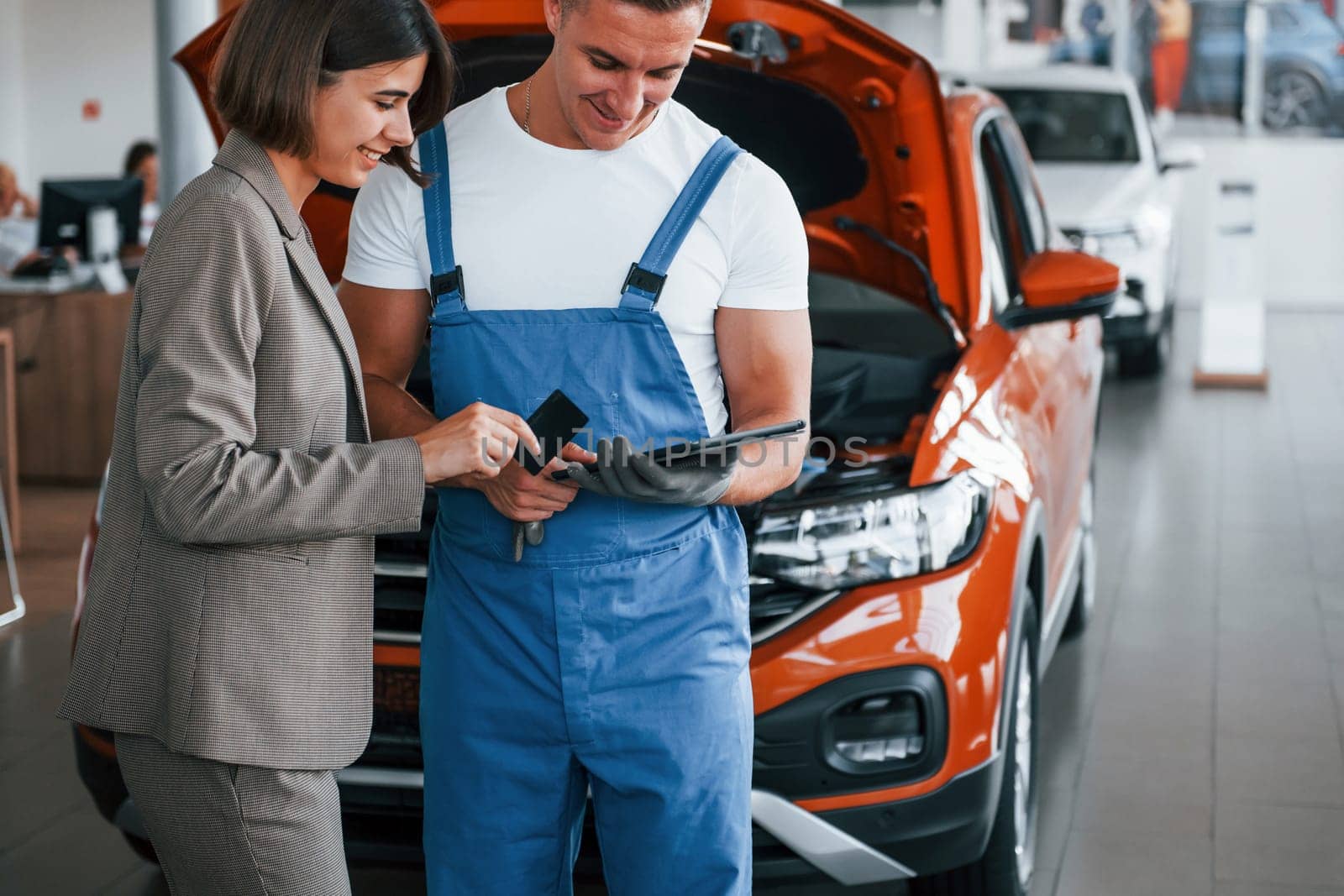 Two people. Man repairing woman's automobile indoors. Professional service.
