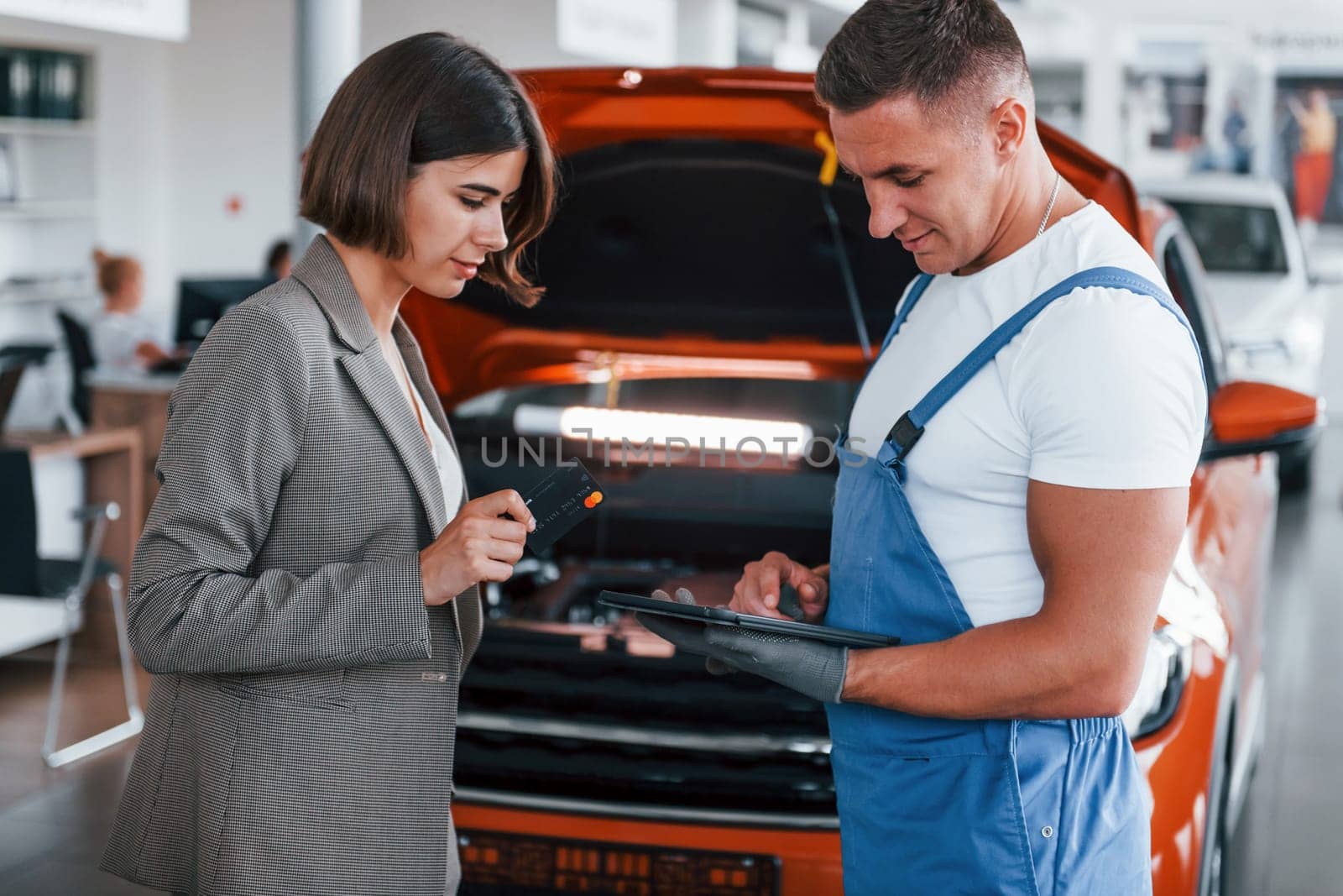 Two people. Man repairing woman's automobile indoors. Professional service.