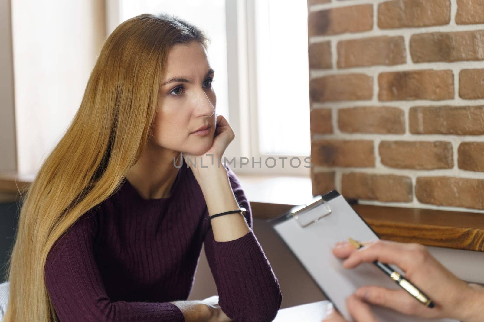 An adult woman at a psychologist's appointment. She listens carefully to what the psychologist says to her. The psychologist makes a note on paper.