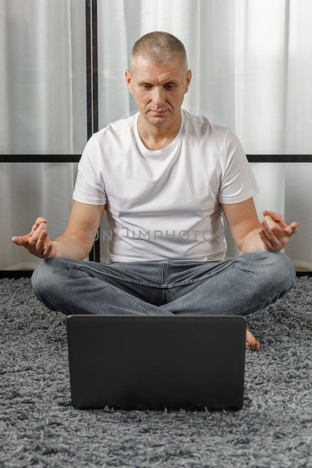 A middle-aged man conducts remote training in yoga, psychosomatics. Vertical frame. Vacation and health concept.