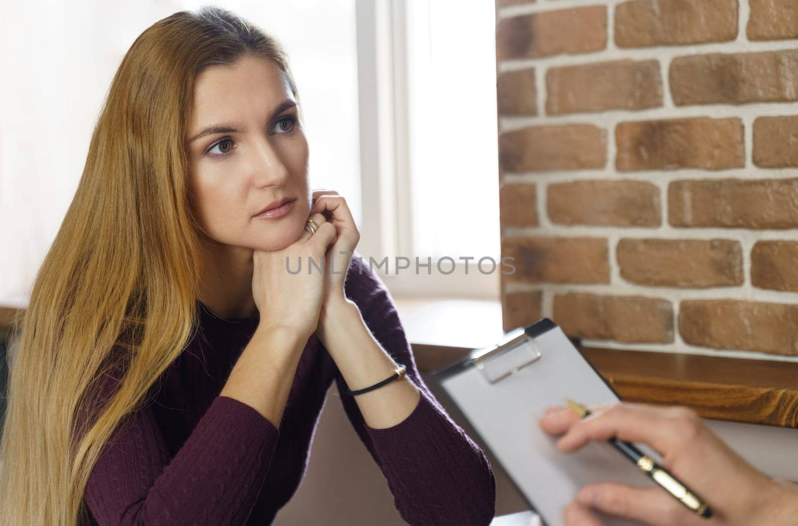 An adult woman at a psychologist's appointment. She listens carefully to what the psychologist says to her. The psychologist makes a note on paper.