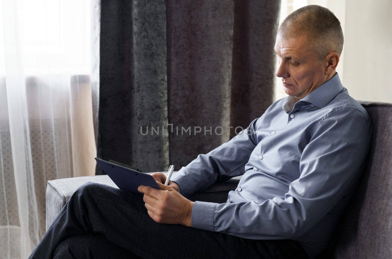 A middle-aged businessman man sits on a sofa and writes in a tablet by Sd28DimoN_1976
