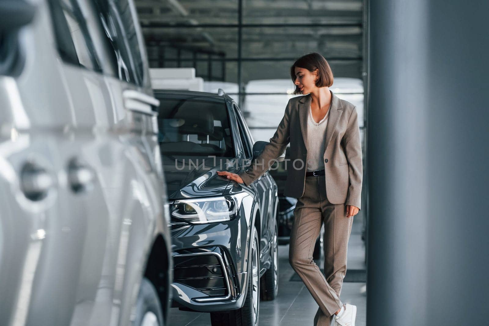 Modern technology. Woman is indoors near brand new automobile indoors.
