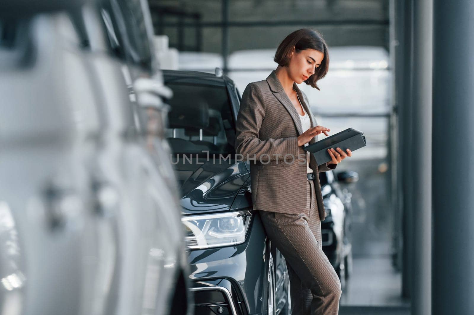 Modern technology. Woman is indoors near brand new automobile indoors.