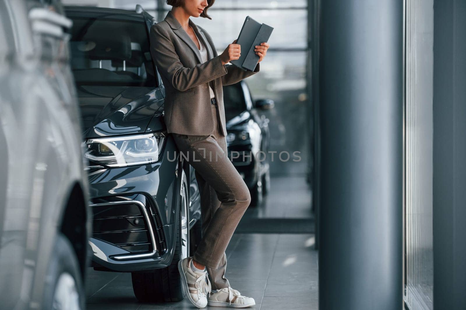 Particle view. Woman is indoors near brand new automobile indoors.
