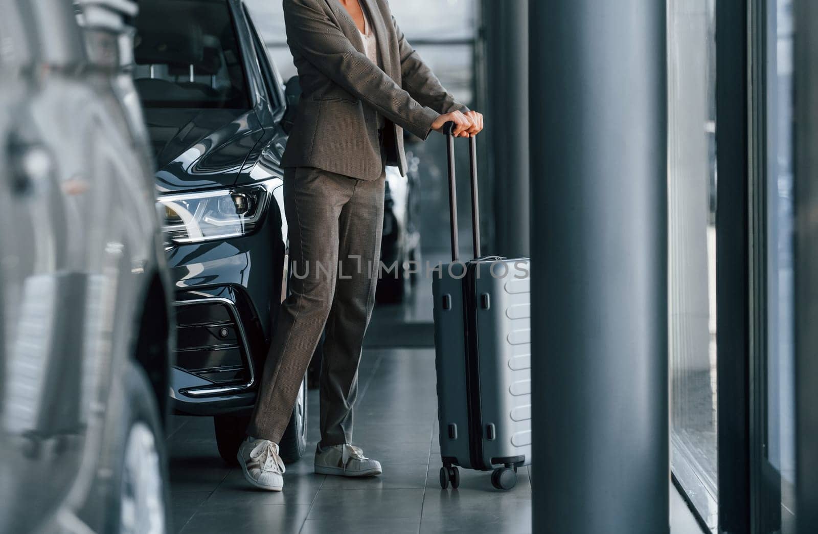 Particle view. Woman is indoors near brand new automobile indoors.