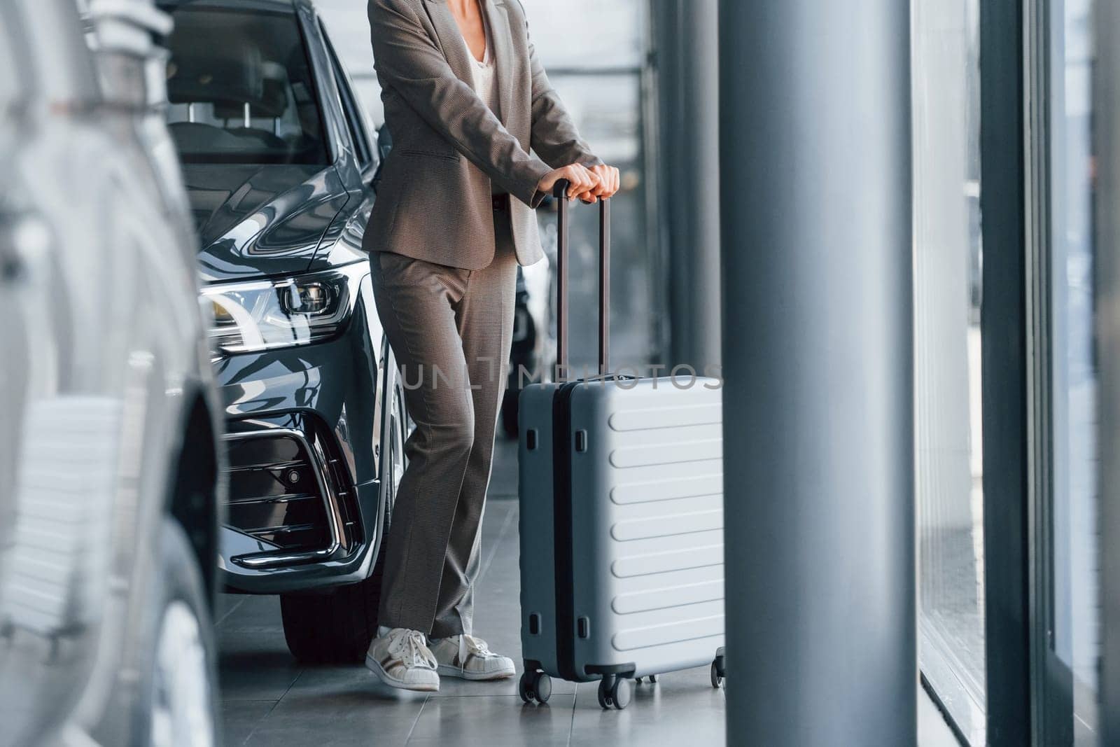Particle view. Woman is indoors near brand new automobile indoors.
