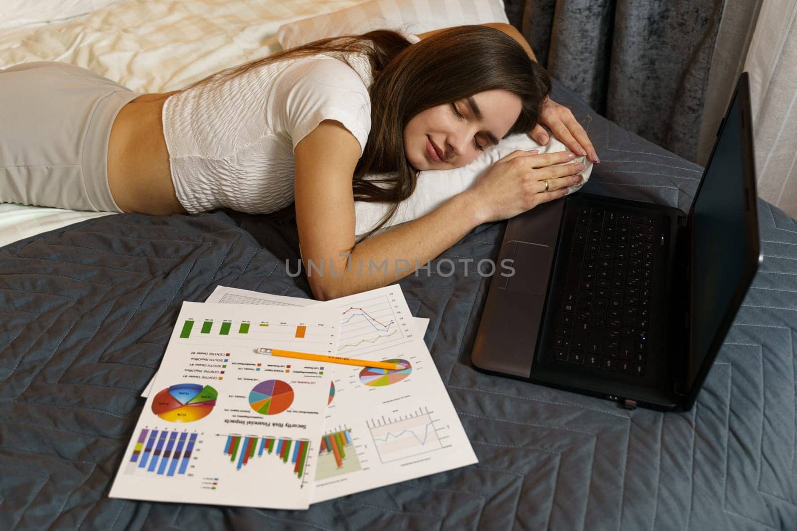 A young girl fell asleep in bed studying reporting information - work. Remote work, training.