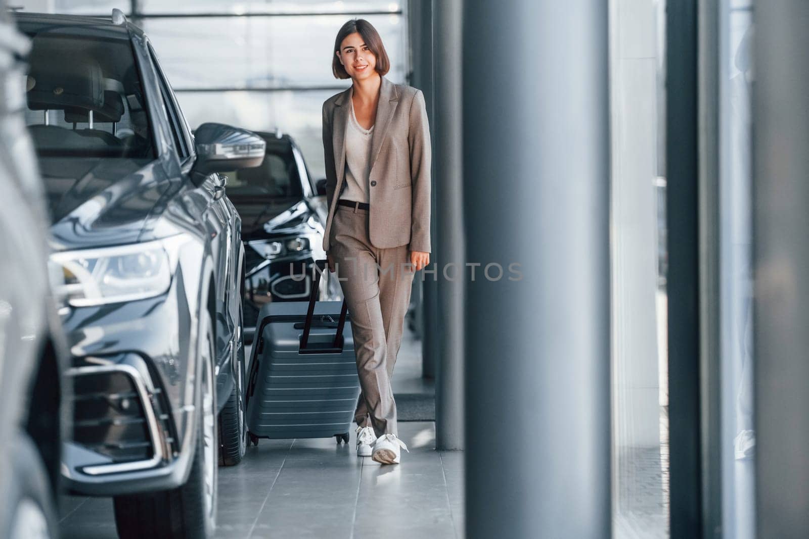 Tourist with lugagge. Woman is indoors near brand new automobile indoors.