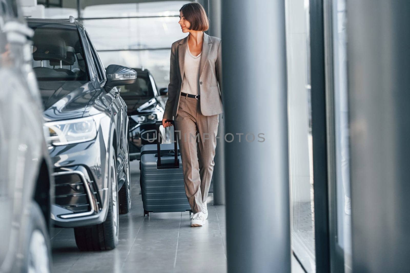 Tourist with lugagge. Woman is indoors near brand new automobile indoors.